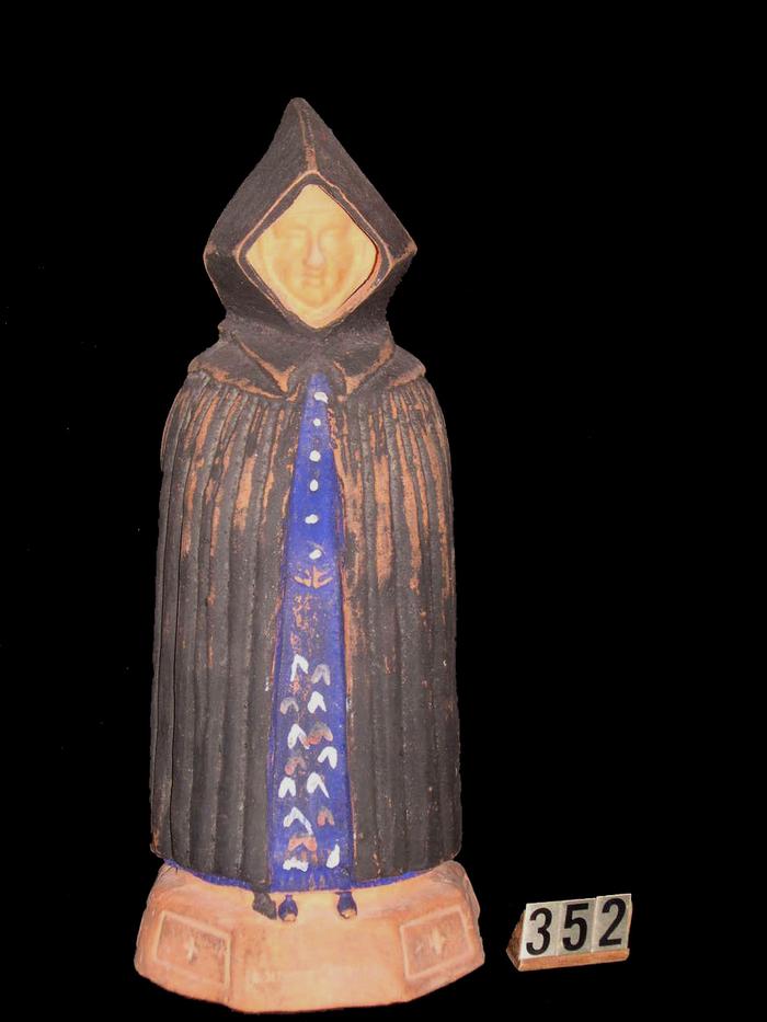 Estatueta de mulher de capote e capelo